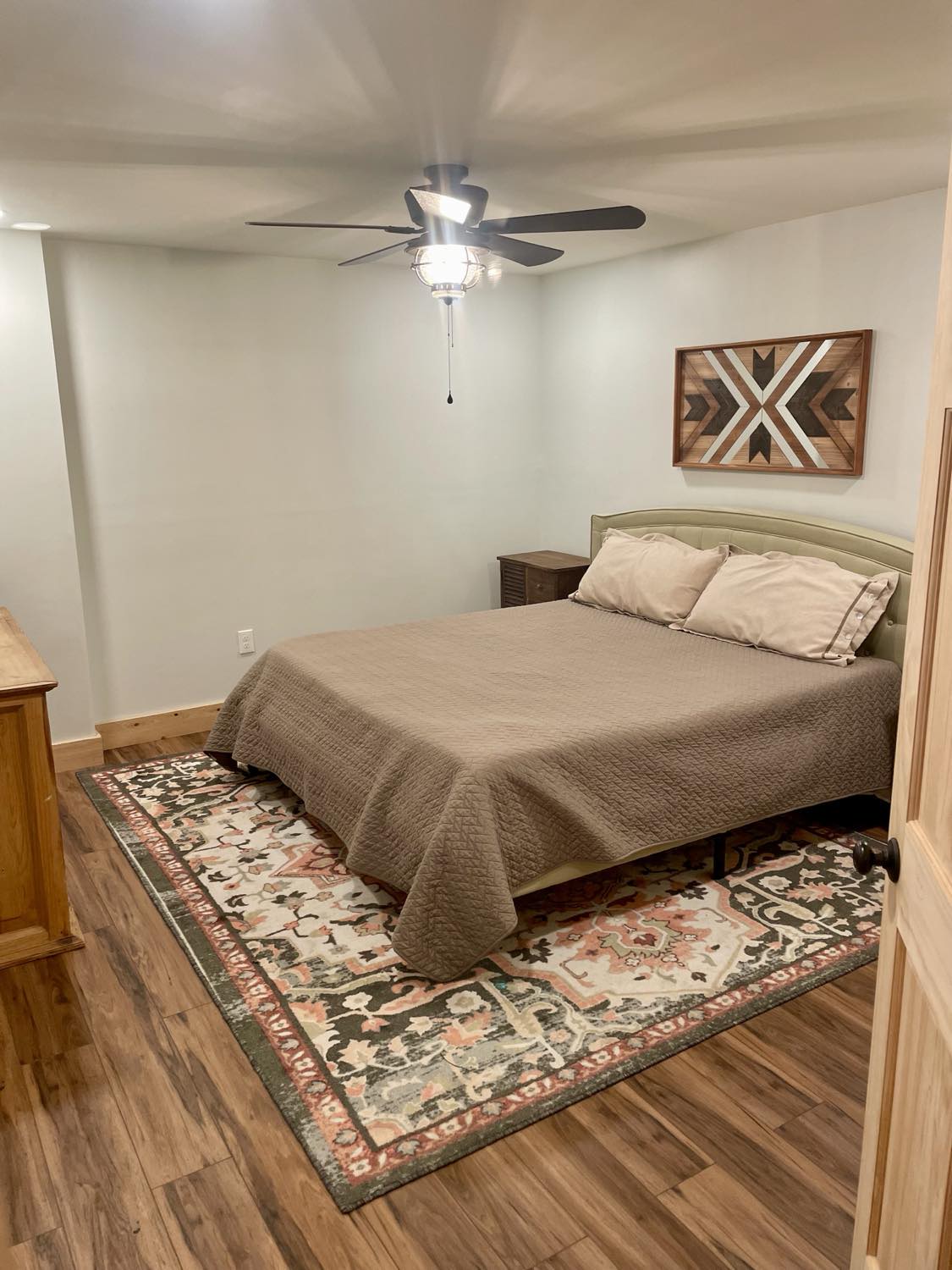 Cama tamaño king muy cómoda con dos mesitas de noche, una cómoda, un armario, una mesa auxiliar detrás de la puerta y una ventana para una vista al patio trasero y al pasto trasero.