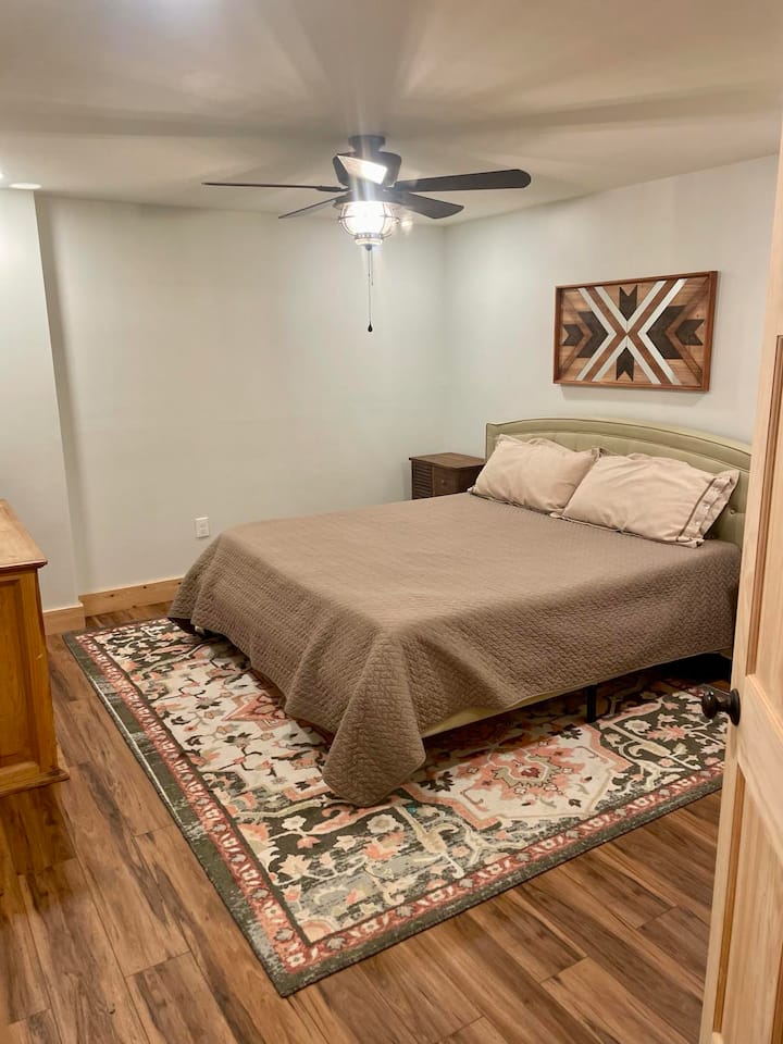 เตียงขนาดคิงไซส์ที่สบายมากพร้อมขาตั้ง 2 คืนตู้เสื้อผ้าตู้เสื้อผ้าโต๊ะข้างเตียงหลังประตูและหน้าต่างสำหรับชมวิวสวนหลังบ้านและทุ่งหญ้าด้านหลัง