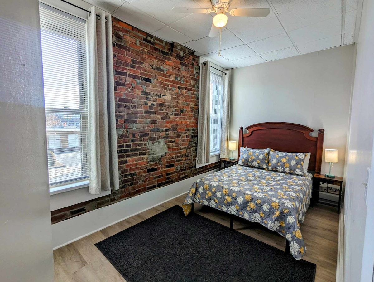 חדר שינה 2 עם מיטה בגודל מלא וקירות לבנים חשופים