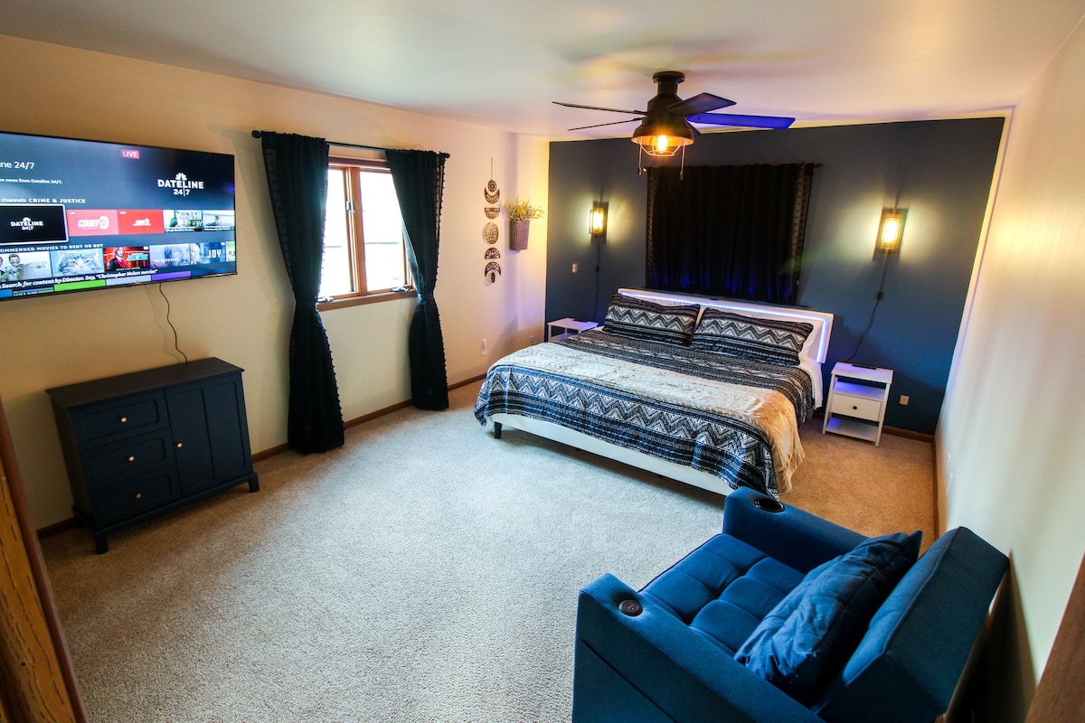 Secondo livello - La camera da letto 2 (Blue Room) dispone di un letto matrimoniale grande con illuminazione a LED, sedia/chaise longue con ricarica USB, SmartTV da 55 pollici, due comodini con stazioni di ricarica e luci, cabina armadio con portabagagli e tende oscuranti