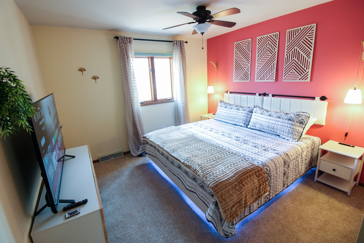 Secondo livello - La camera da letto 1 (camera rosa) dispone di un letto matrimoniale grande, illuminazione a LED, SmartTV da 55 pollici, due comodini con stazioni di ricarica e luci, cassettiera, armadio con portavaligie, tende oscuranti e sveglia all'alba con suoni del sonno