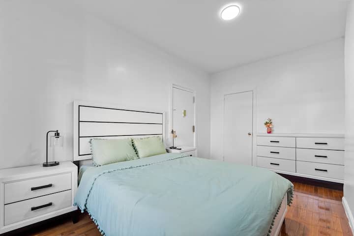 Спална соба со големина на Квинс со 55-инчен телевизор, звучна машина, гардеробер, ноќни шкафчиња, ноќни светилки