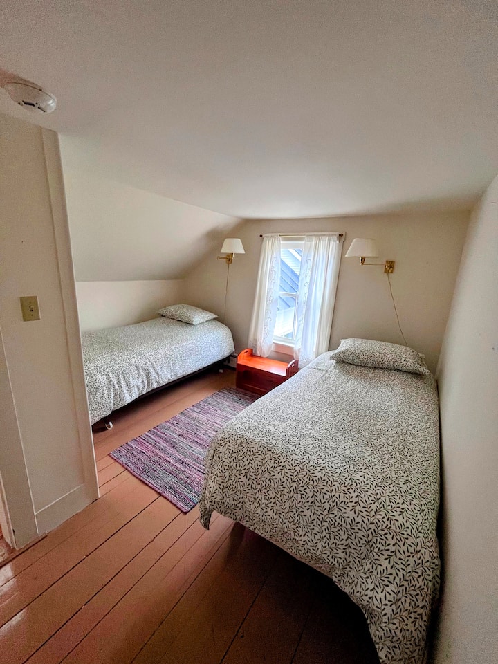Twin bedroom on 2nd floor with wall lamps and views of the back yard and sugarwoods