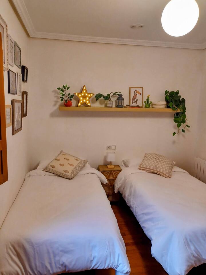 Camas individuales con cojines y luz cálida en el dormitorio 2.