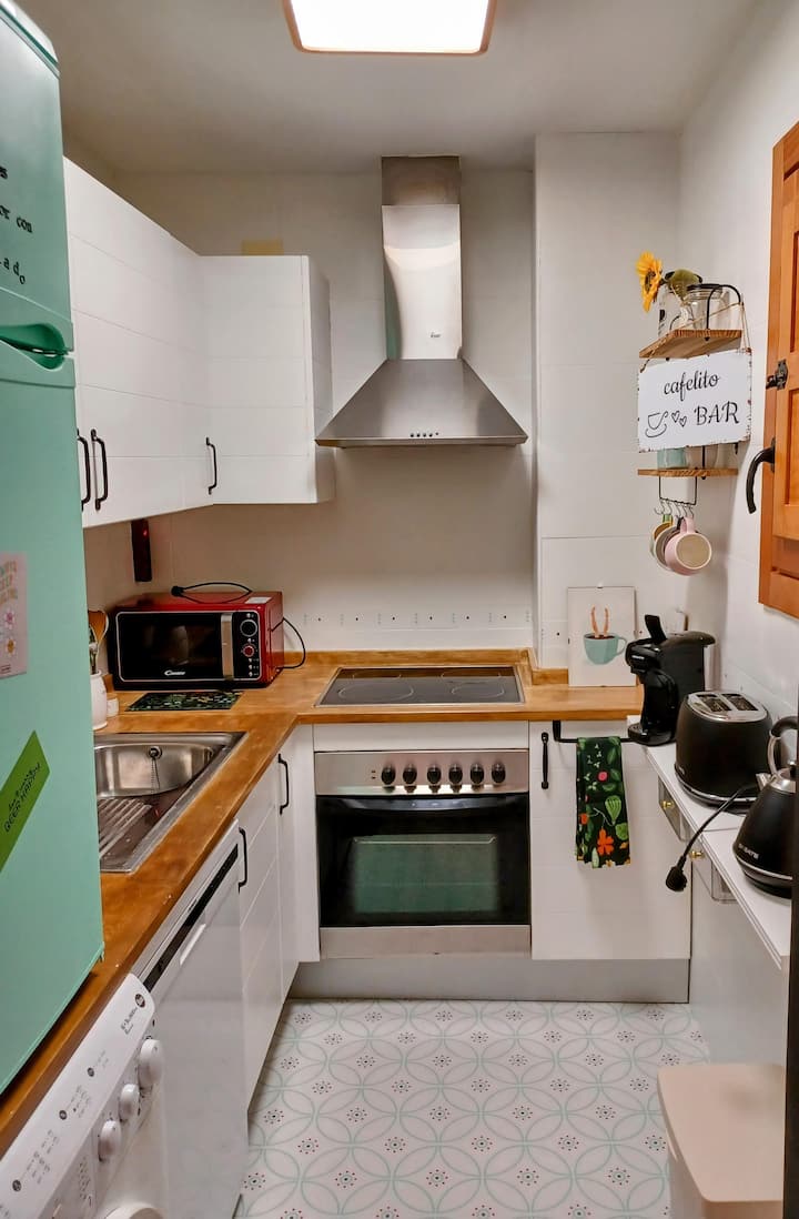 Cocina equipada con horno, placa y varias cafeteras.