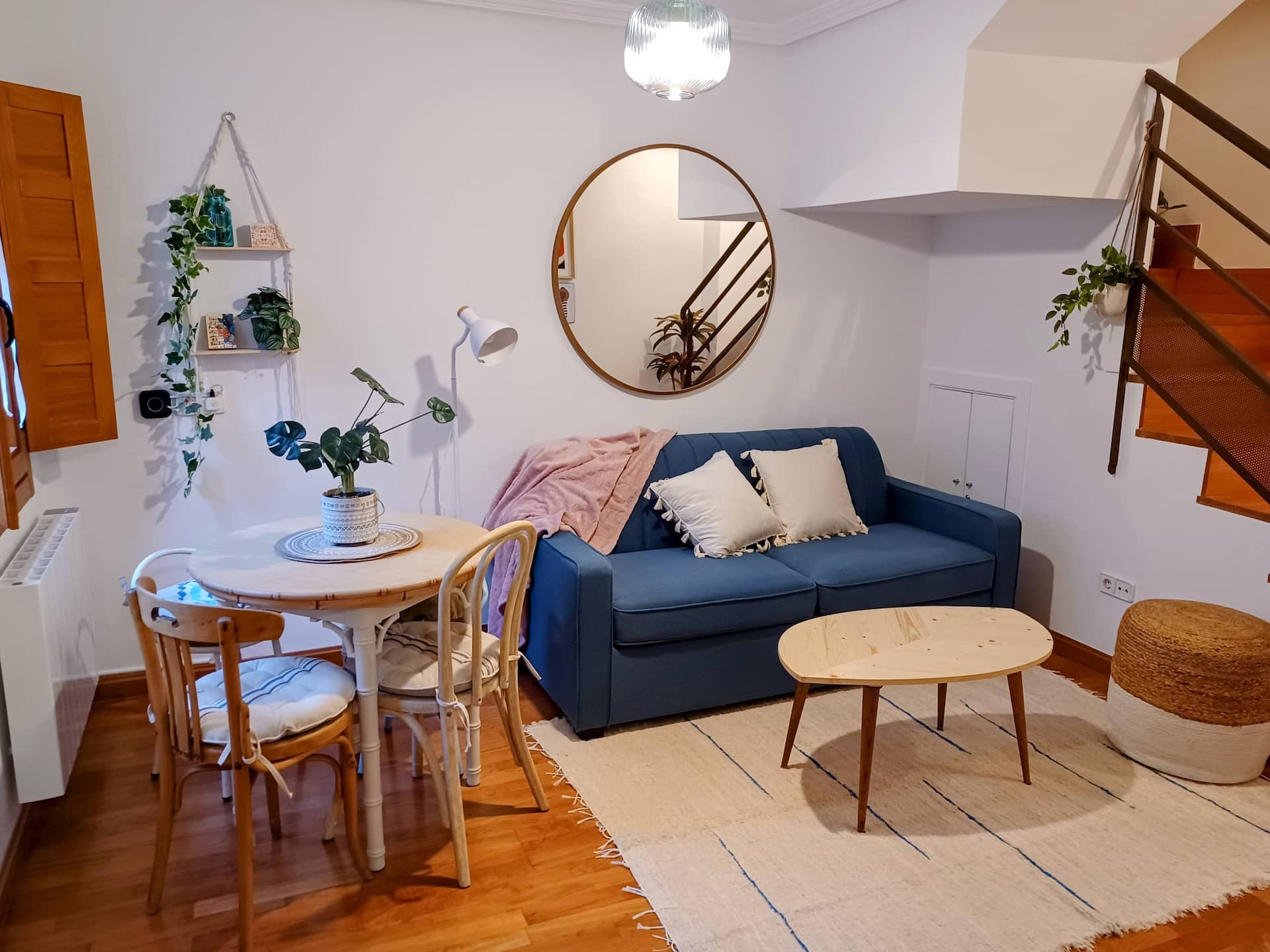 Salón-comedor con sofá cama, mesa y luz natural.