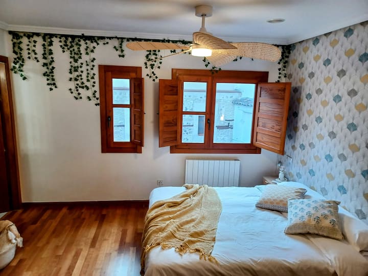Dormitorio principal con ventana de madera y radiador: calidez todo el año.