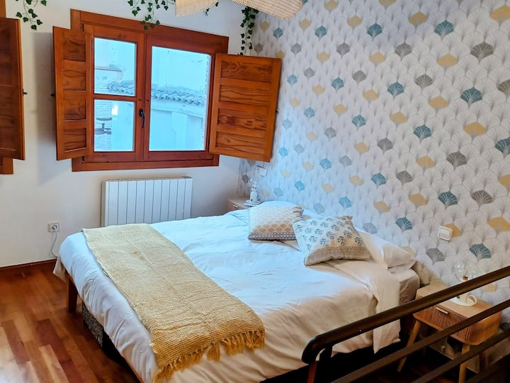 Cama doble con manta dorada y cojines: llegar y dejarse caer.