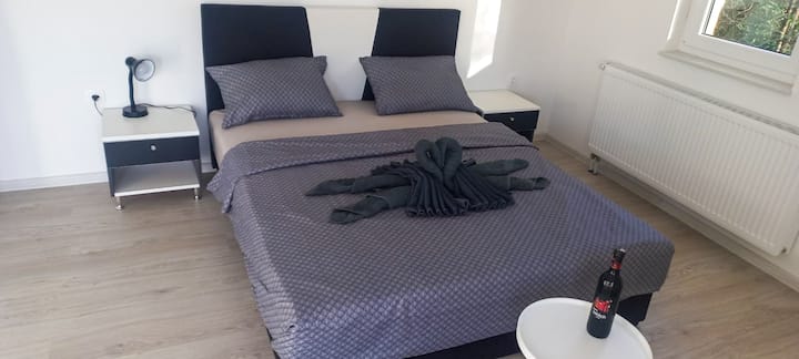 Dhoma e dytë e gjumit ka një krevat të madh e të rehatshëm, me dy komodina dhe hyrje në një ballkon, si dhe një komodinë për rroba.