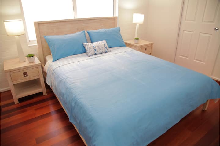 Chambre queen size avec peignoir intégré, ventilateur de plafond et salle de bain attenante.