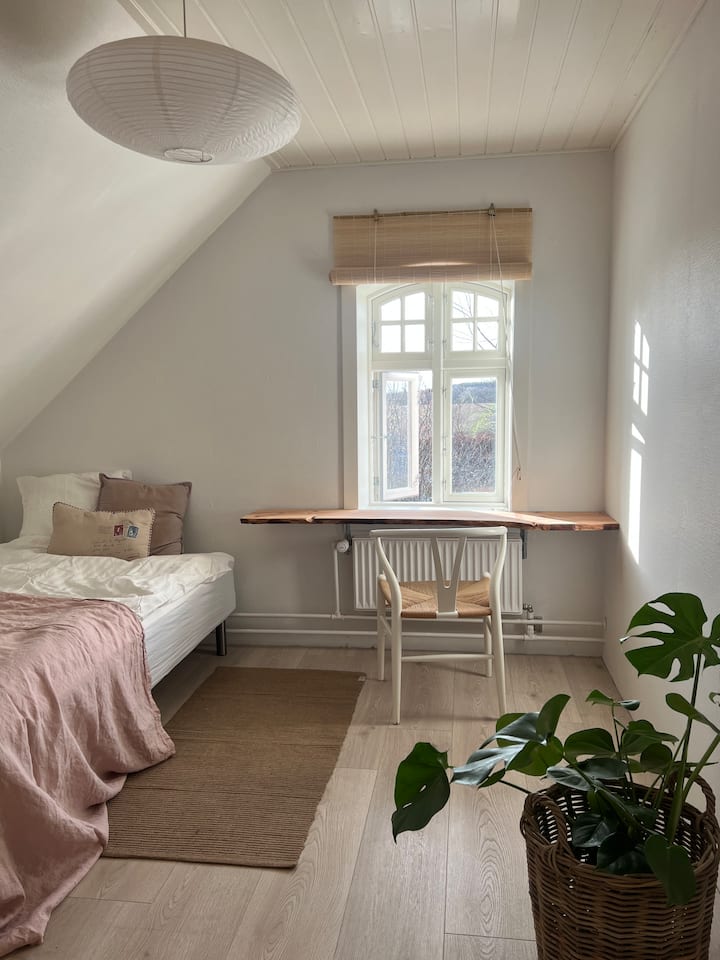 Chambre rose avec lit simple, avec bonne volonté, il y a de la place pour deux dans le lit. Taille du lit : 120 cm
Bureau avec vue sur le jardin.