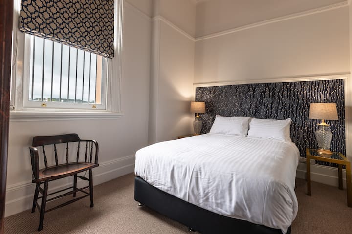 Queen size bed with adequate lightening. Views of the blue hills in the distance and the historic town hall.