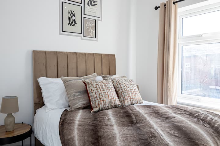 Útulná spálňa s manželskou posteľou, mäkkou posteľnou bielizňou, teplými tónmi a prirodzeným svetlom pre pokojný pobyt