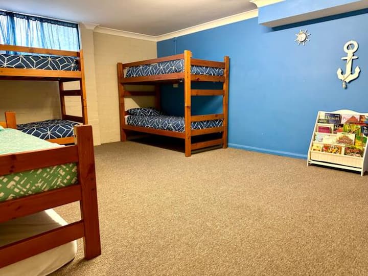 Habitación infantil con 5 literas, libros para niños, juegos, TV y juguetes.