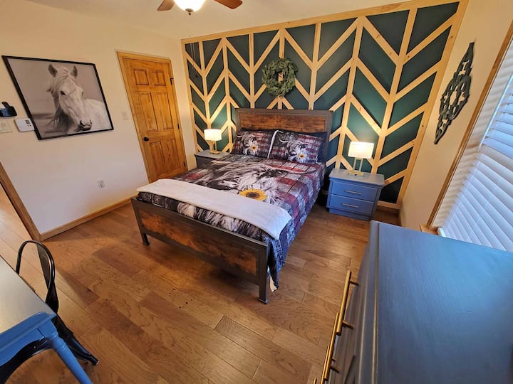 Chumba cha kulala cha "Breeze Haven" kina ubao mahususi wa chevron na ukuta wa batten, fanicha maridadi na kituo cha kazi cha dawati.