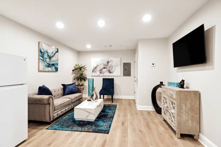 الوحدة 2B مساحة المعيشة - إعدادات المكان لأربعة أشخاص، وتلفزيون عالي الدقة مثبت مع خدمات البث، وأريكة وكرسي، مصممة بعناية، بجوار المطبخ