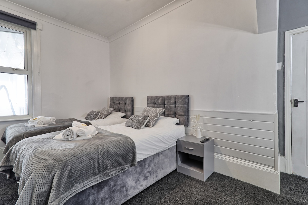 这间舒适的卧室配有灰色主题床和额外的毛巾，让您感到舒适方便。