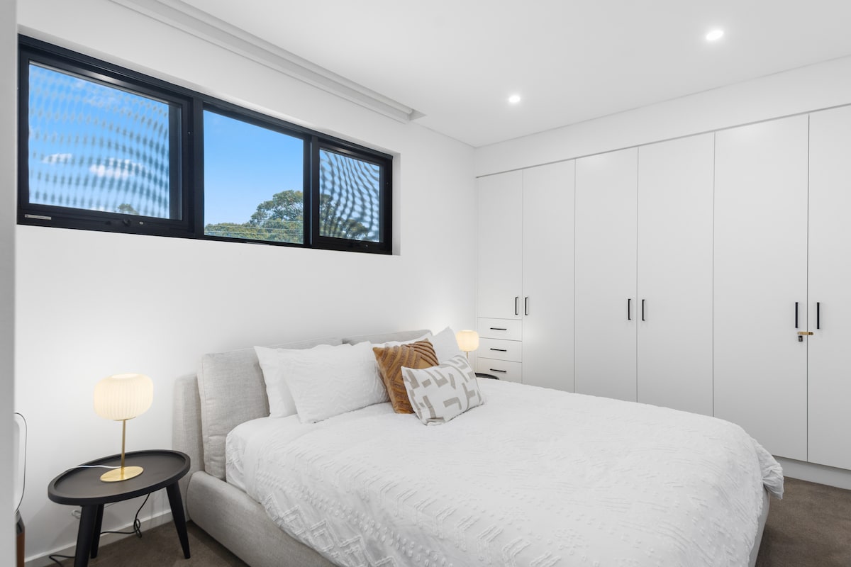 The fresh, white first bedroom is set with a king bed, ample wardrobe space and a wall-hung TV for easy viewing
