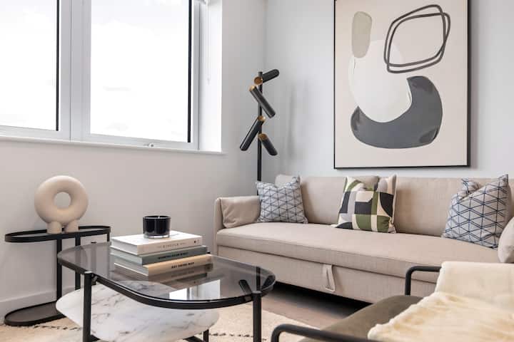 סלון מואר עם ספה נוחה, חלונות גדולים לאור טבעי וטלוויזיה לבידור, מושלם למנוחה.