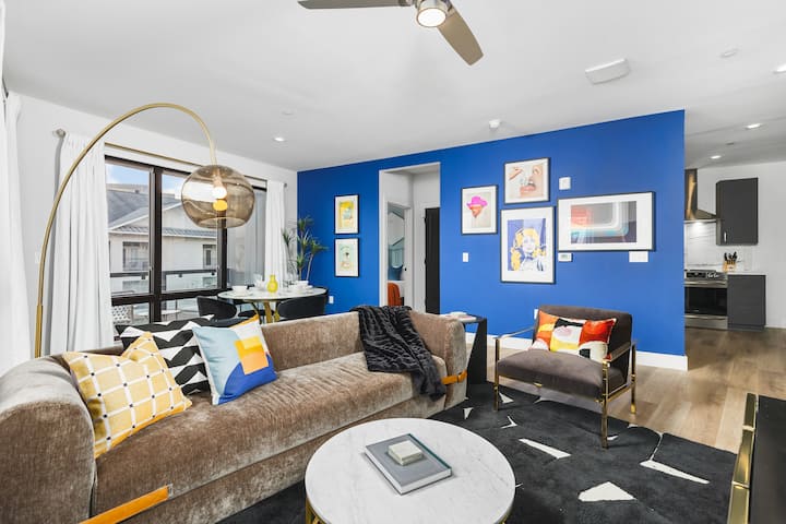 Priestranná, farebná obývacia izba s inteligentným televízorom, obrovskými oknami, ovinutou verandou a jedálenským stolom s posedením pre 4 osoby.