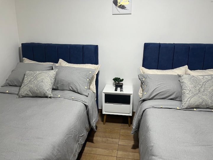 Habitación 2: consta de dos cómodas camas semidobles con un Tv Smart de 32" con aplicaciones de streaming como Netflix, mesa de noche  y ventana con vista al interior del apartamento.
