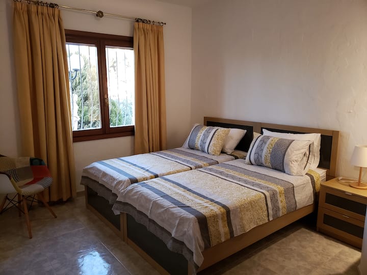 חדר שינה בקומה נמוכה עם שתי מיטות נפרדות - אידיאלי לילדים, חברים או סידורי שינה גמישים. מיזוג אוויר, חימום ואחסון מספקים סידור נוח ופרקטי.