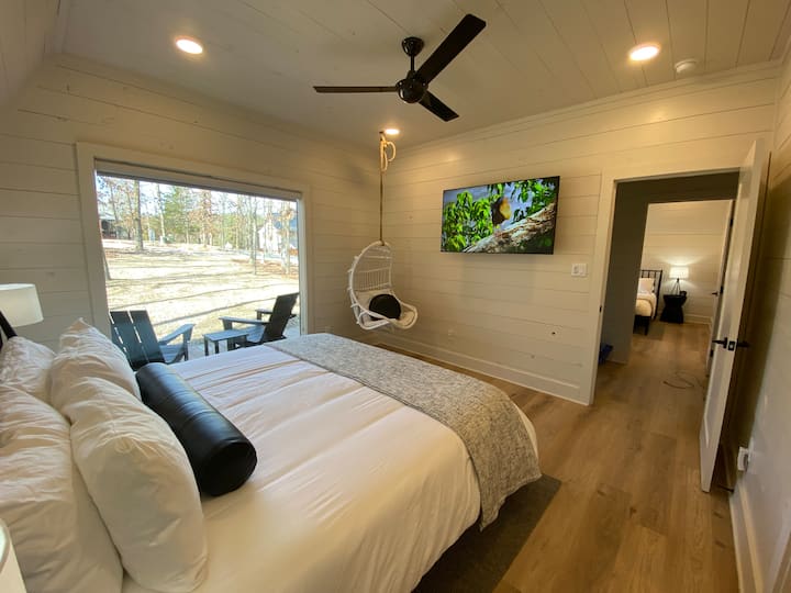 Relax in a cozy modern bedroom with a scenic view and stylish decor.