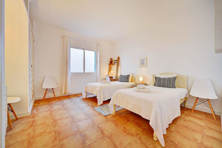 Dormitorio con dos camas individuales y espacio de trabajo exclusivo.