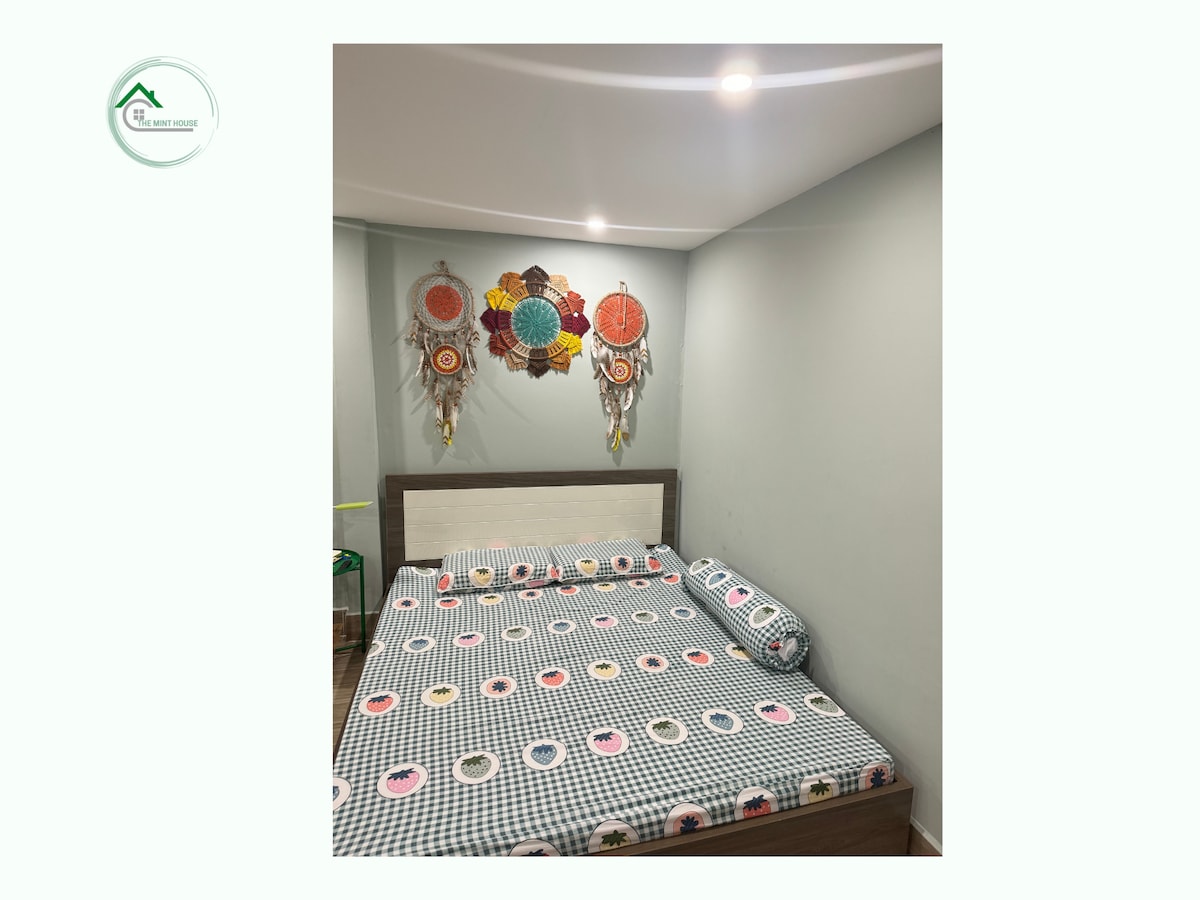 A sleeping area is presented with a spacious bed dressed in a patterned duvet cover. Colorful wall hangings add visual interest above the bed. Soft lighting from recessed fixtures enhances the inviting atmosphere of the room.