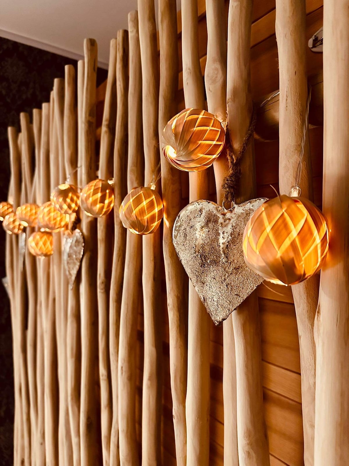 Soft lighting is provided by decorative globes and a heart-shaped ornament, which are suspended against a backdrop of wooden slats. The natural textures create a calming visual arrangement, enhancing the tranquility of the space.