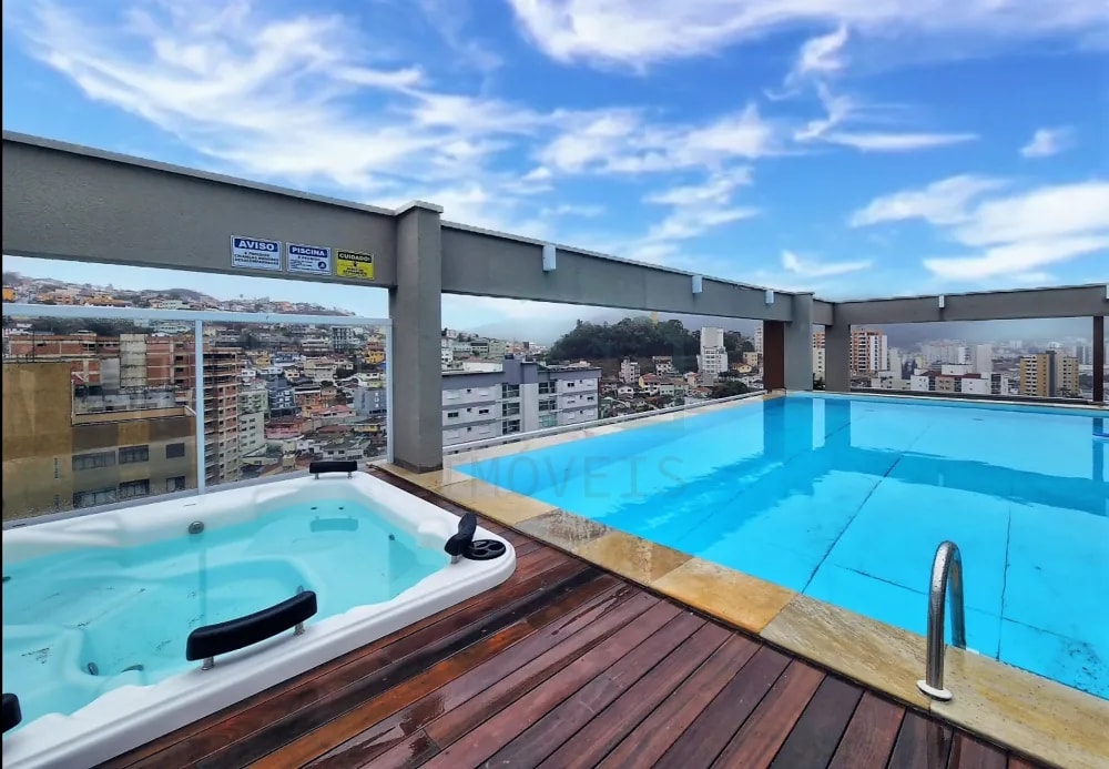 A rooftop pool area features a large swimming pool and a hot tub, surrounded by wooden decking. Panoramic views of the city skyline and hills are visible through large open spaces, enhancing the relaxing atmosphere.