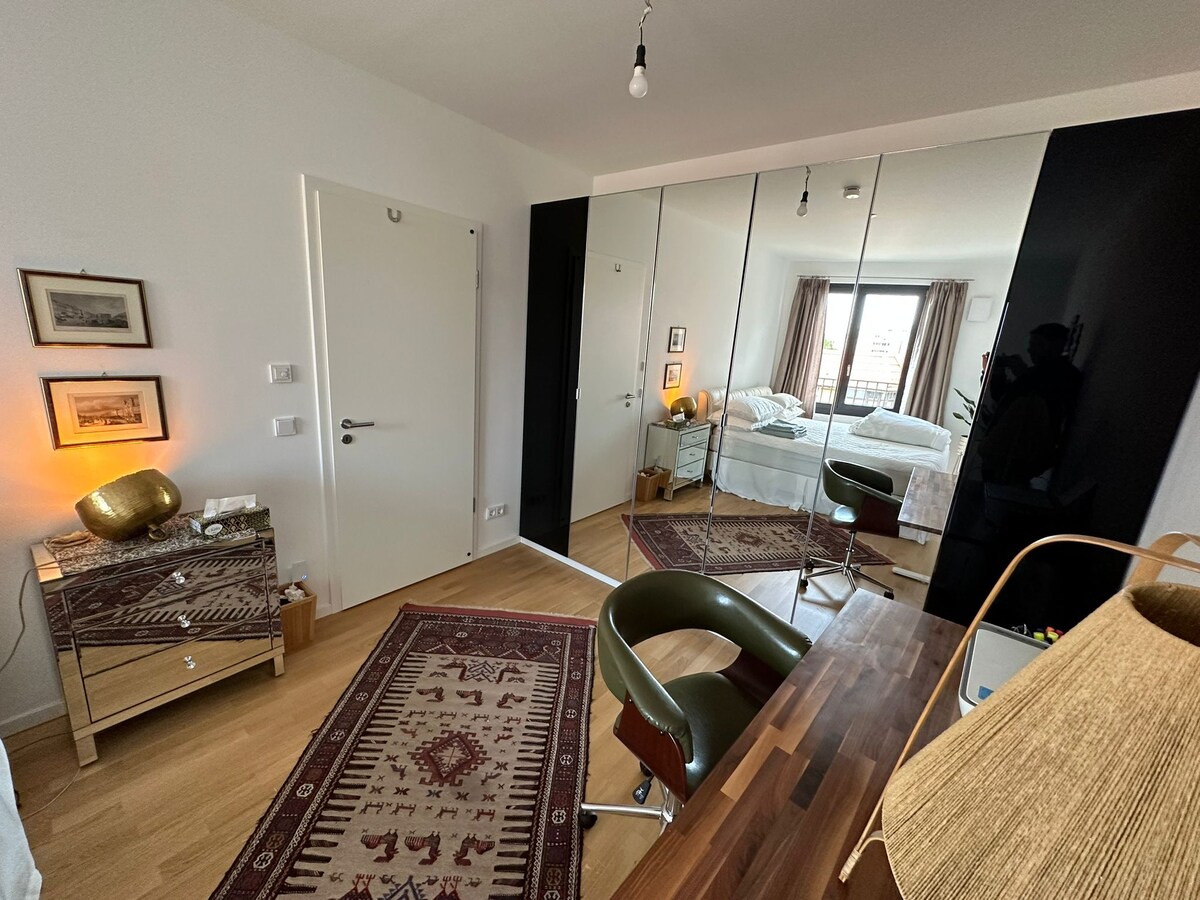 El gran dormitorio de la suite Master King, con una cama California King DUX súper grande y un escritorio personalizado ajustable en altura.