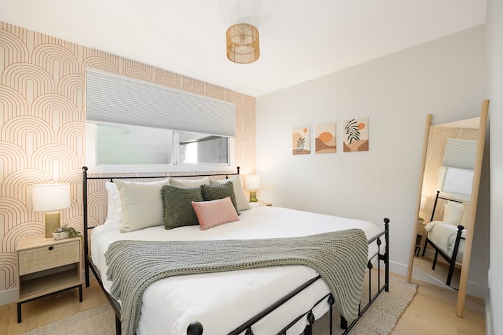 This bedroom has a king bed with a comfortable mattress, blackout shades, a feature wall and a full length mirror. In the closet you will find extra linens, hangers, a fan, and luggage racks.