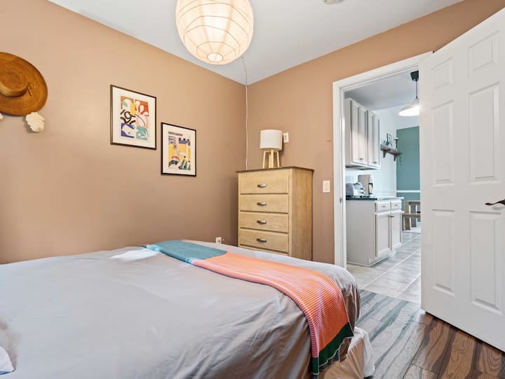 Este dormitorio se encuentra en secreto al final de la cocina como una joya oculta. Con algunas obras de arte y colores vibrantes, este dormitorio tamaño queen con armario de tamaño medio y cajonera aporta un ambiente artístico.
