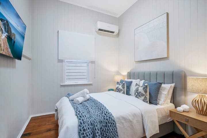 Spavaća soba s bračnim krevetom i pametnim 50-inčnim 4K televizorom marke Samsung s Netflixom.