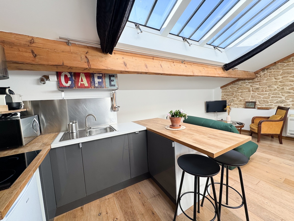 A well-appointed kitchen space features modern cabinetry and a wooden countertop. Light floods in from the skylights, illuminating the area. A decorative 'CAFE' sign adds character, while a small potted plant provides a touch of greenery. Nearby, a comfortable seating area is visible.