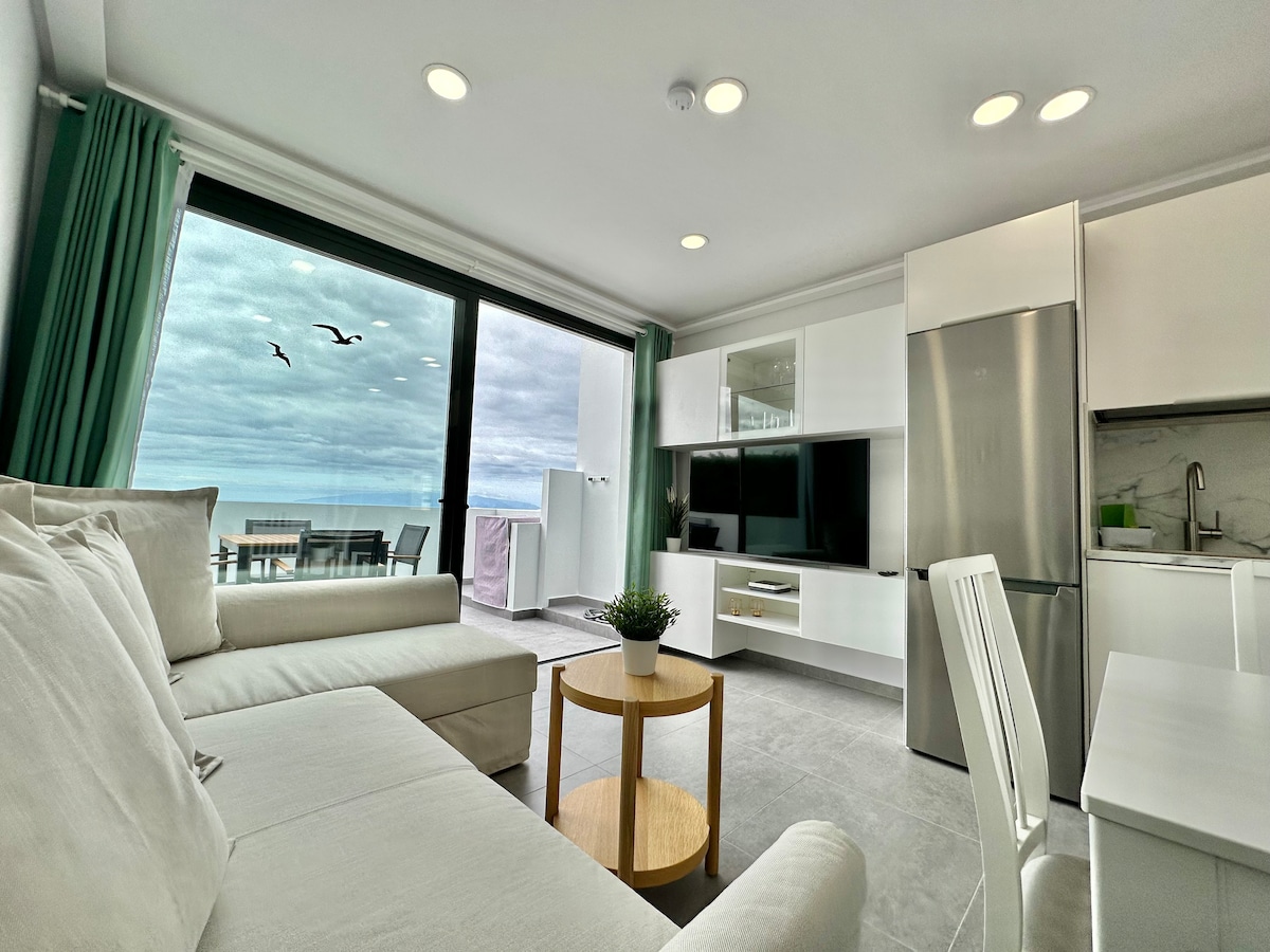 غرفة معيشة بها تلفزيون ذكي وإطلالات على المحيط وجزيرة لا غوميرا