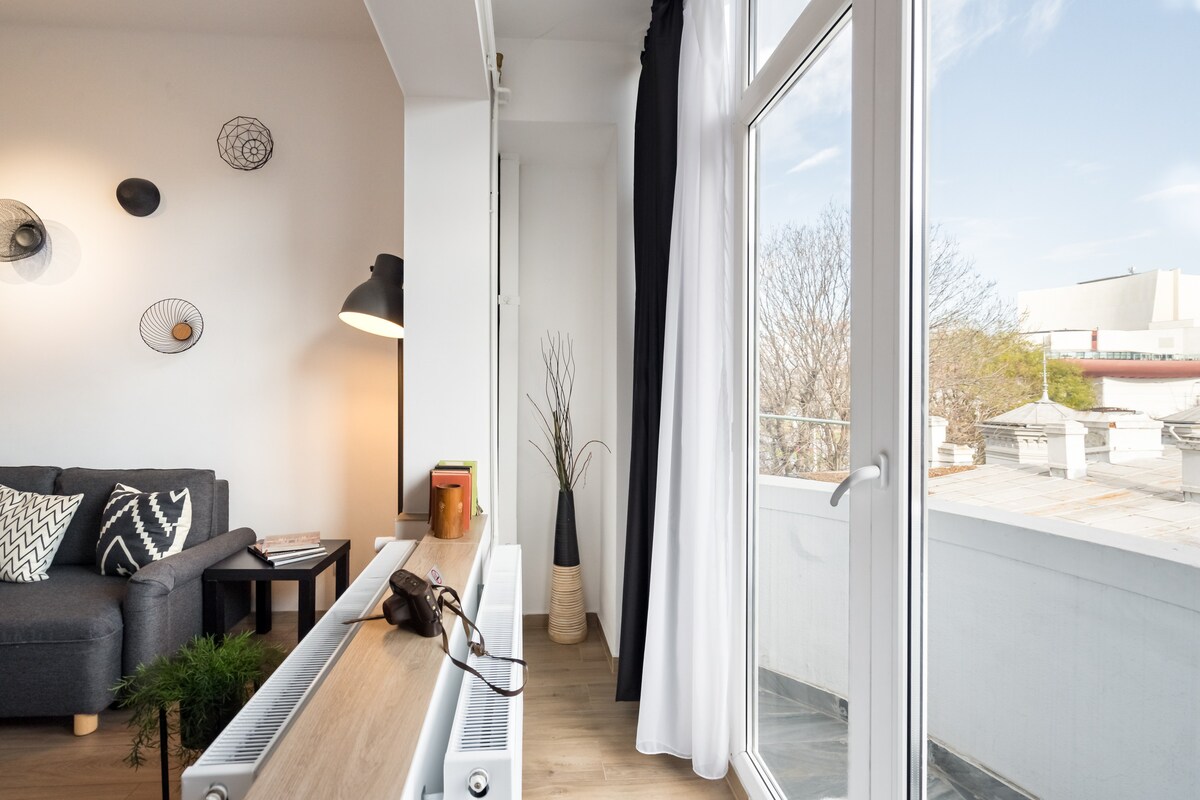 მსუბუქი მისაღები ოთახიდან პირდაპირ კერძო აივანზე გადასვლაა იატაკიდან ჭერამდე მინის კარების მეშვეობით. გეომეტრიული ნახატები კედლებზე, მყუდრო ნაცრისფერი დივანი და მწვანილი ქმნის ჰაეროვან გარემოს, რომელიც იდეალურია დასასვენებლად და ხედების დასათვალიერებლად.