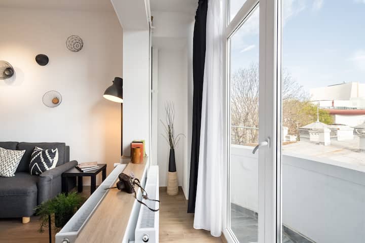 Dhoma e ndenjjes me ndriçim të mirë hapet në një ballkon privat përmes dyerve prej xhami nga dyshemeja në tavan. Arti gjeometrik i murit, një divan gri komod dhe gjelbërimi krijojnë një ambient të ajrosur të përsosur për t'u çlodhur dhe për të shijuar pamjet.