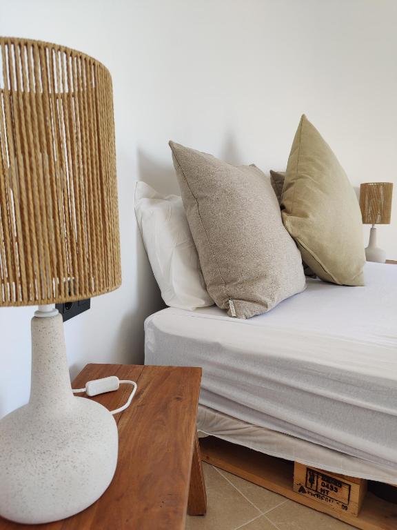 A cozy sleeping area features a spacious bed with soft, neutral-colored pillows. Two stylish lamp bases made of natural materials provide ambient lighting on either side of the bed. The light color scheme enhances the tranquil atmosphere of the room.