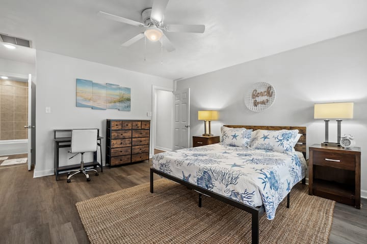 Quarto principal com cama queen size, mesa e cadeira, piso lvp, cômoda, 2 armários, varanda de 2º andar fora do quarto, cama de rodízio com 2 gêmeos e TV montada.
