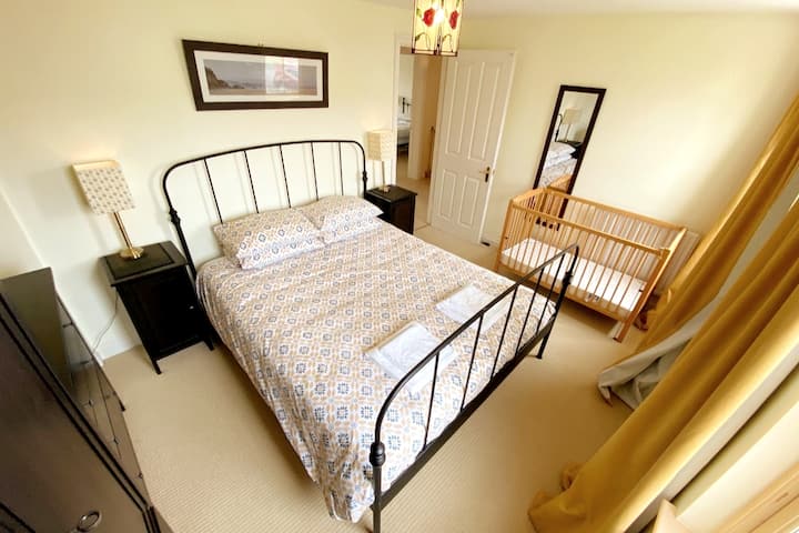 Chumba cha pili cha kulala kilicho na kitanda cha ukubwa wa kifalme na mandhari nzuri ya kijiji tulivu. Kila chumba cha kulala kina kabati la nguo, vioo, kifua cha droo na taa za kitanda. Cot inaweza kuhamishiwa kwenye chumba chochote cha kulala.