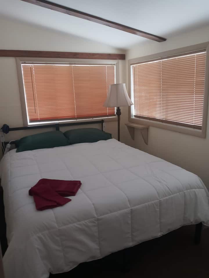 Dormitorio queen con manta climatizada, 2 puertos USB, armario, soporte de equipaje, calefacción, aire acondicionado de ventana y 2 ventanas. 