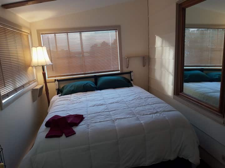Dormitorio queen con manta climatizada, 2 puertos USB, armario, soporte de equipaje, calefacción, aire acondicionado de ventana y 2 ventanas. 