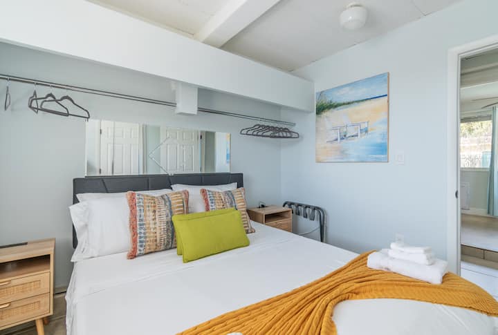 The queen bedroom sits at the quiet back of the house, with mirrors and hanging racks that make living out of a suitcase optional.