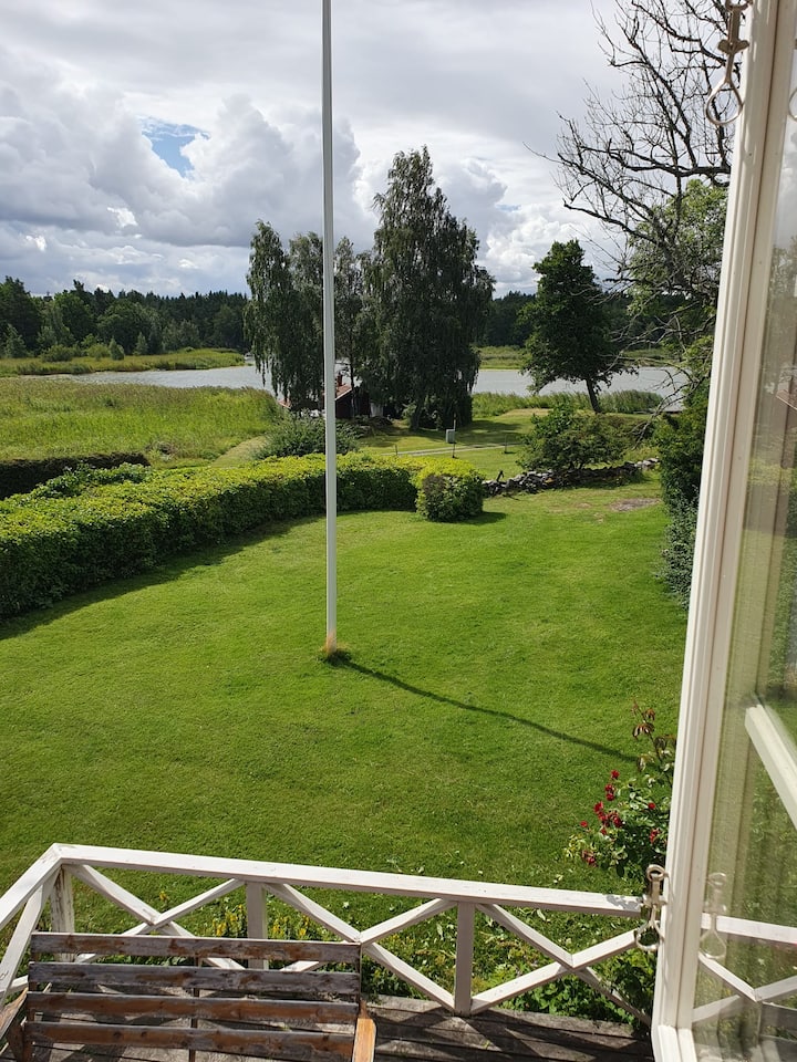 Tazama kutoka kwenye chumba cha kulala cha nyumba kubwa ya shambani kuelekea kwenye maji. Hapa chini kuna sehemu ya baraza. 