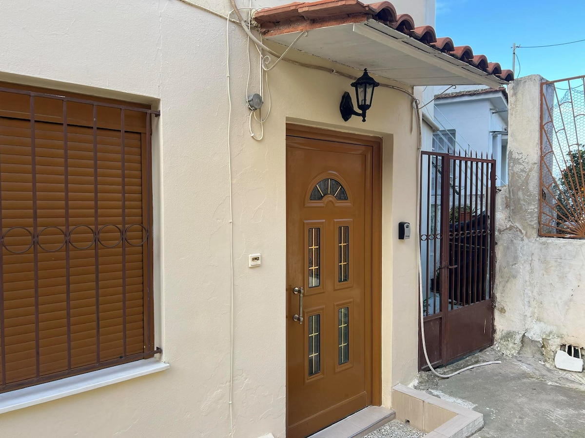 The entrance showcases a secure, brown door with glass panels. A lantern is mounted above, providing subtle illumination. A gated area is visible to the right, while shuttered windows flank the left side, enhancing the property's private and welcoming appeal.