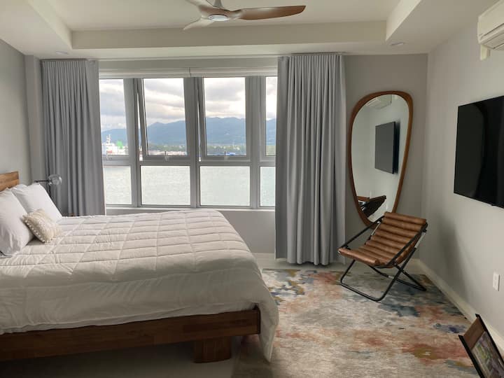 Დიდი ზომის საწოლი. უშუქო ქვრივი მკურნალობა. 55"სმარტ-ტელევიზორი. ჭერის ვენტილატორი და კონდიციონერი. Საწოლთან მაგიდის სანათებს აქვს უსბ დამტენი პორტი. Ოკეანისა და მთების ულამაზესი ხედი. 