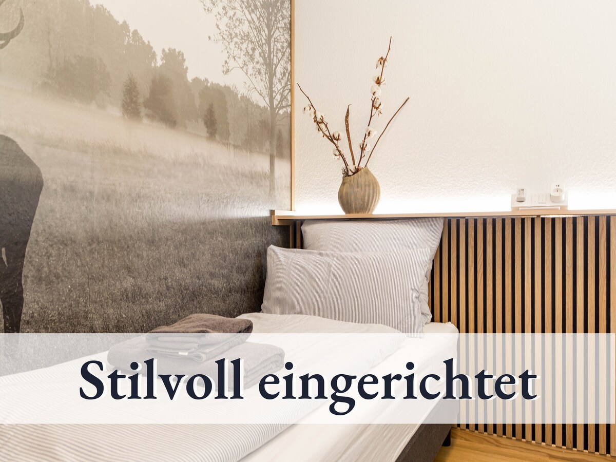 סלון מרווח עם ספה נפתחת נעימה בגודל קווין סייז וכיסא תלוי.  