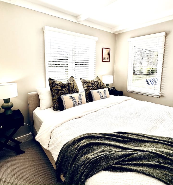 King size bedroom with ensuite bathroom and view out to backyard and pool